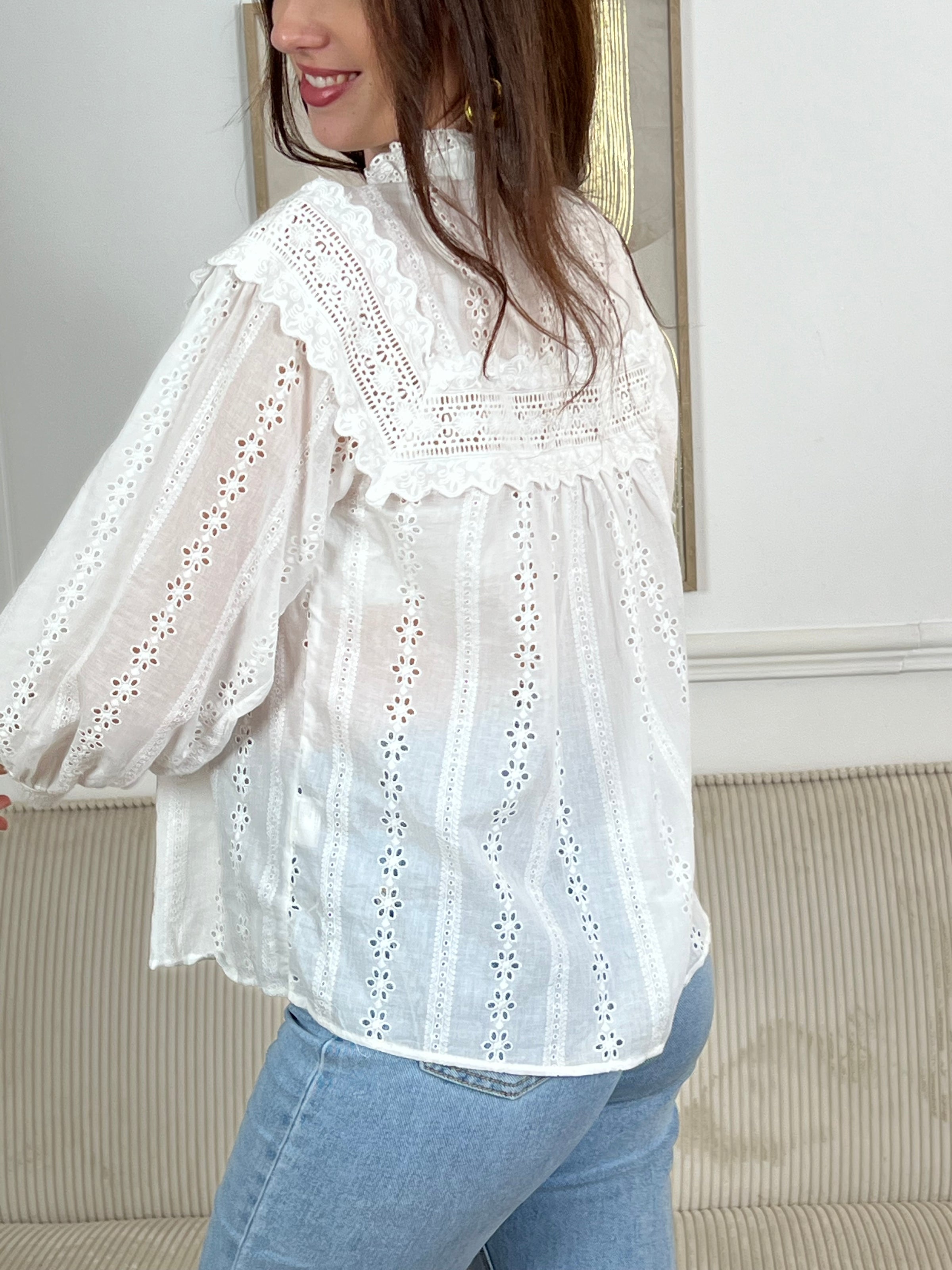 Chemise Angele en coton 100% pour les femmes. Manches bouffantes, col volant et broderie ajourée confèrent à cette pièce écrue une élégance intemporelle. Légèrement transparente, elle se porte avec aisance au quotidien comme en occasion.