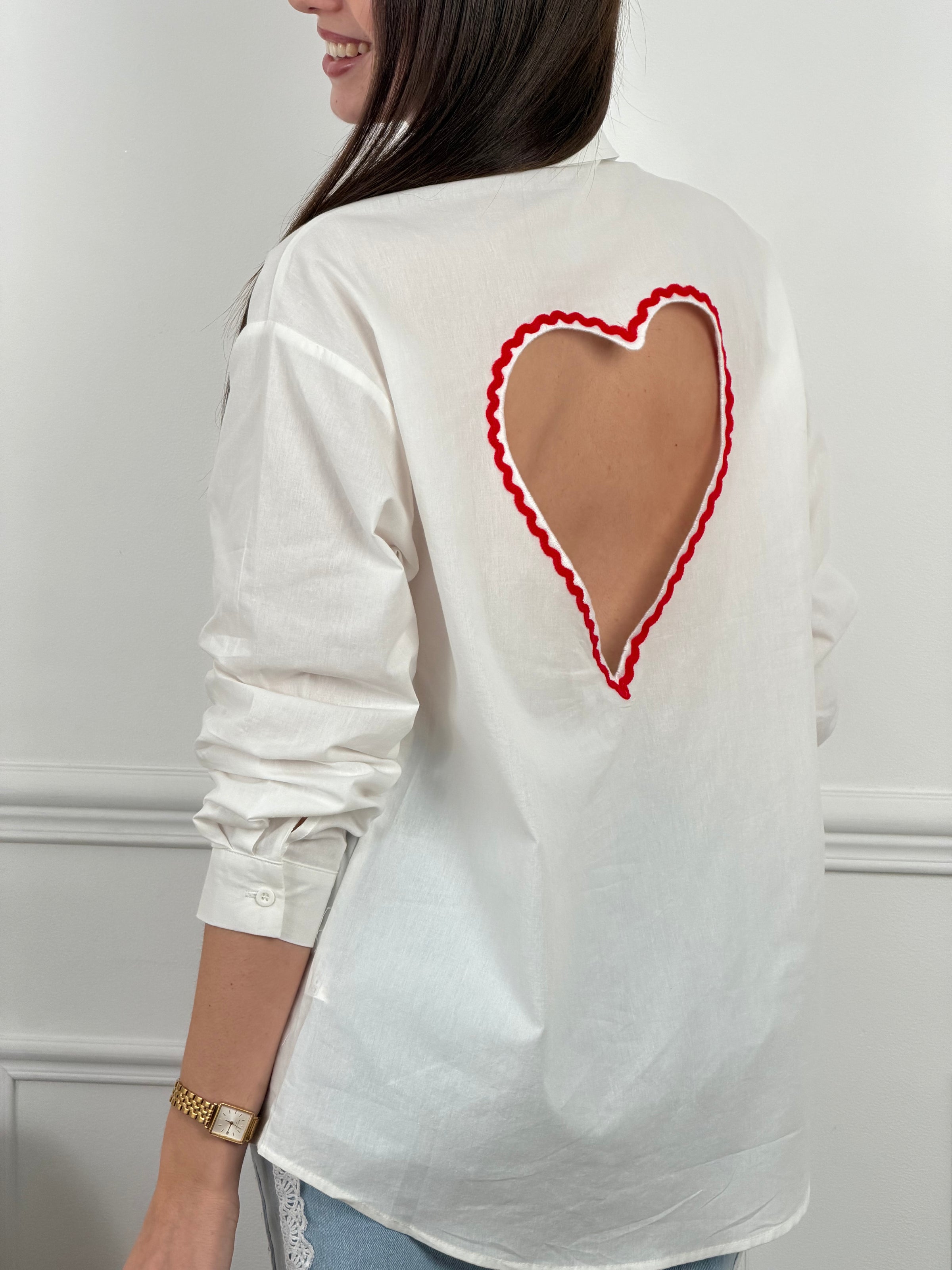 Chemise en coton aux détails romantiques et féminins. Manches longues avec boutons aux poignets, col chemise classique et fermeture boutonnée sur toute la longueur. La touche signature : une découpe en cœur rouge au dos qui ajoute une dimension poétique à cette pièce incontournable. Parfaite pour créer des looks à la fois élégants et originaux.
