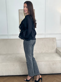 Légère et pleine de charme, cette chemise noire pour femme apporte une touche lumineuse et féminine à votre tenue. Son col V délicatement souligné par un élastique met en valeur le décolleté, tandis que les poignets élastiqués assurent un joli tombé aux manches longues. Les volants au col, aux épaules et aux manches ajoutent du mouvement et une note romantique à l’ensemble. Sa matière légèrement transparente renforce son côté aérien et élégant.