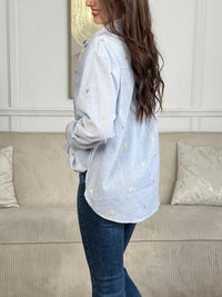 La chemise Sélène en coton combine style intemporel et détails délicats. Rayures verticales bleu et écru, cœurs dorés brodés et col chemise structuré créent une allure sophistiquée. Manches longues avec boutons aux poignets, poche poitrine et fermeture boutonnée complète.