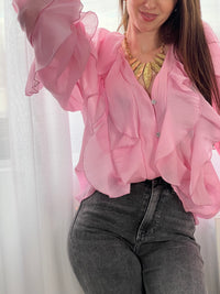 Légère et pleine de charme, cette chemise rose pour femme apporte une touche lumineuse et féminine à votre tenue. Son col V délicatement souligné par un élastique met en valeur le décolleté, tandis que les poignets élastiqués assurent un joli tombé aux manches longues. Les volants au col, aux épaules et aux manches ajoutent du mouvement et une note romantique à l’ensemble. Sa matière légèrement transparente renforce son côté aérien et élégant.