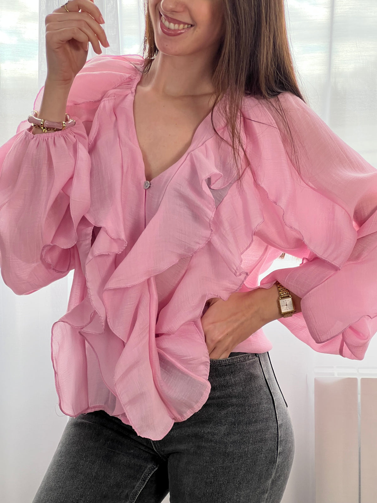 Légère et pleine de charme, cette chemise rose pour femme apporte une touche lumineuse et féminine à votre tenue. Son col V délicatement souligné par un élastique met en valeur le décolleté, tandis que les poignets élastiqués assurent un joli tombé aux manches longues. Les volants au col, aux épaules et aux manches ajoutent du mouvement et une note romantique à l’ensemble. Sa matière légèrement transparente renforce son côté aérien et élégant.