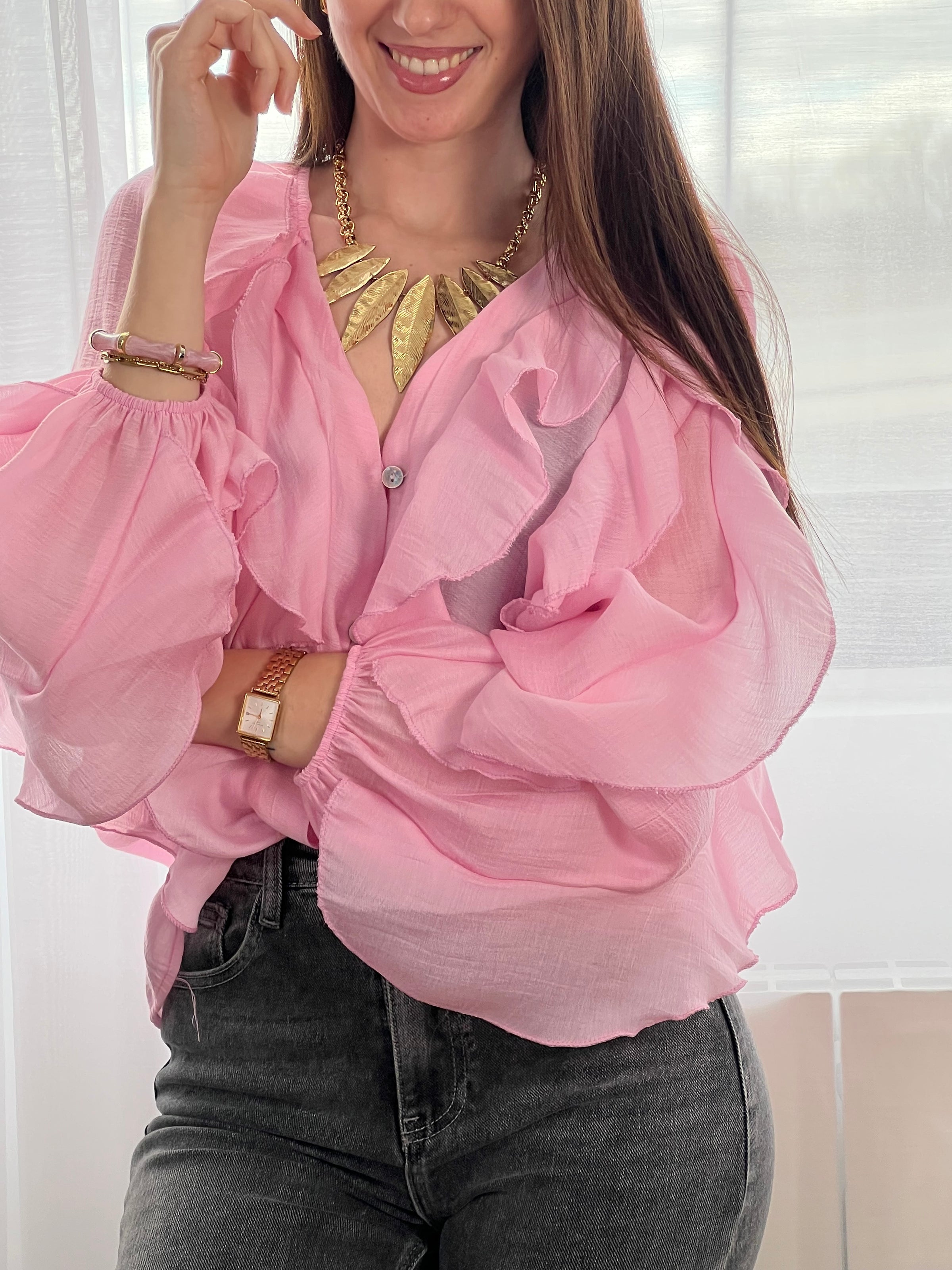 Légère et pleine de charme, cette chemise rose pour femme apporte une touche lumineuse et féminine à votre tenue. Son col V délicatement souligné par un élastique met en valeur le décolleté, tandis que les poignets élastiqués assurent un joli tombé aux manches longues. Les volants au col, aux épaules et aux manches ajoutent du mouvement et une note romantique à l’ensemble. Sa matière légèrement transparente renforce son côté aérien et élégant.