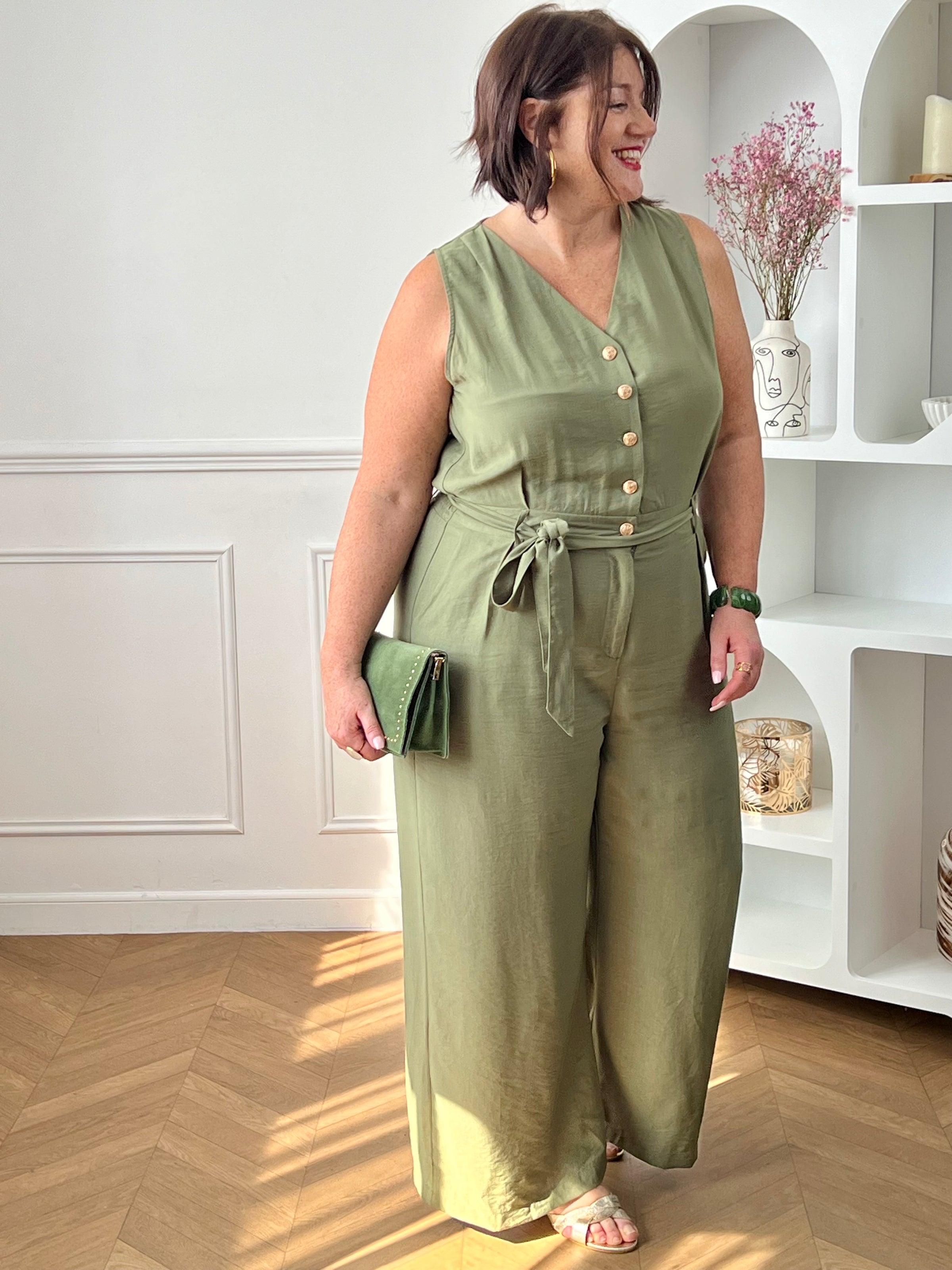 Combinaison longue femme, élégante et moderne, parfaite pour un look tendance au quotidien. Sans manches, avec un col V et des boutons dorés sur le haut, elle apporte une touche chic et raffinée. Dotée d’une ceinture amovible avec passants et d’une taille élastique au dos, elle assure un ajustement confortable. Ses deux poches latérales et sa fermeture zippée à l’avant allient praticité et style.