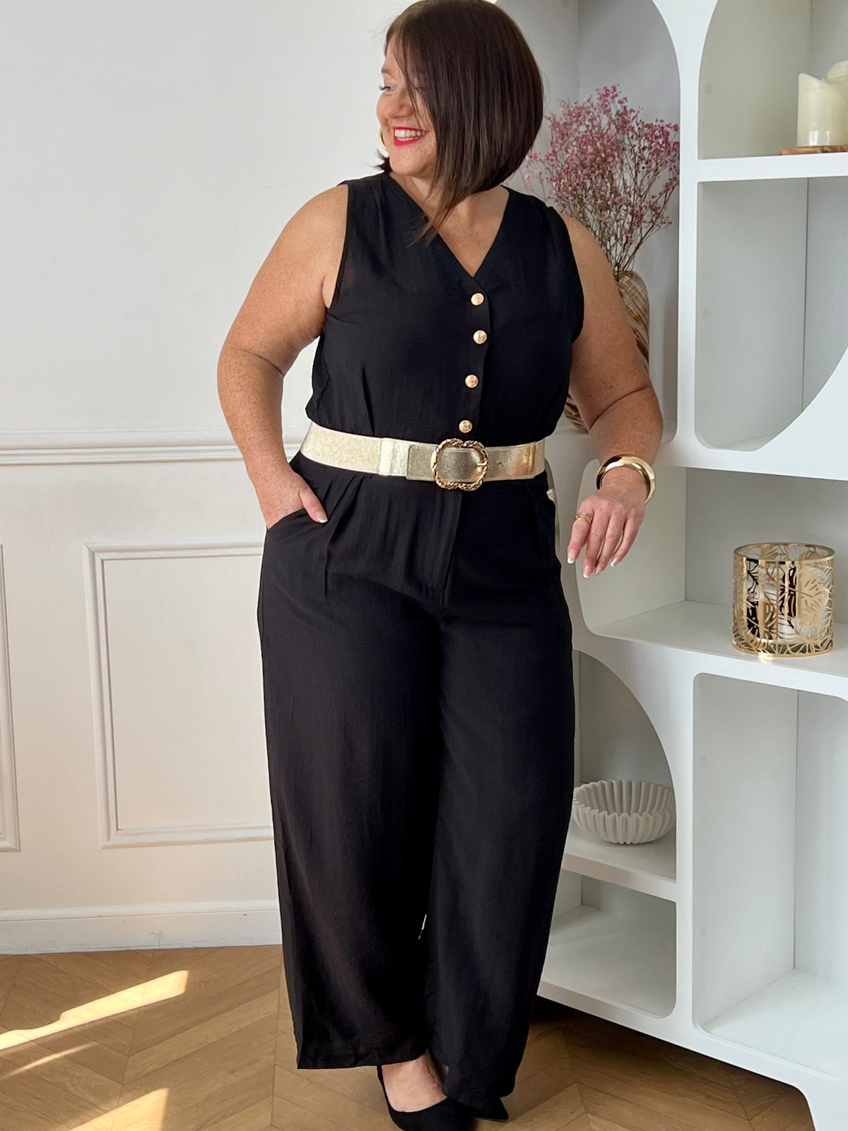 Combinaison longue femme, élégante et moderne, parfaite pour un look tendance au quotidien. Sans manches, avec un col V et des boutons dorés sur le haut, elle apporte une touche chic et raffinée. Dotée d’une ceinture amovible avec passants et d’une taille élastique au dos, elle assure un ajustement confortable. Ses deux poches latérales et sa fermeture zippée à l’avant allient praticité et style.