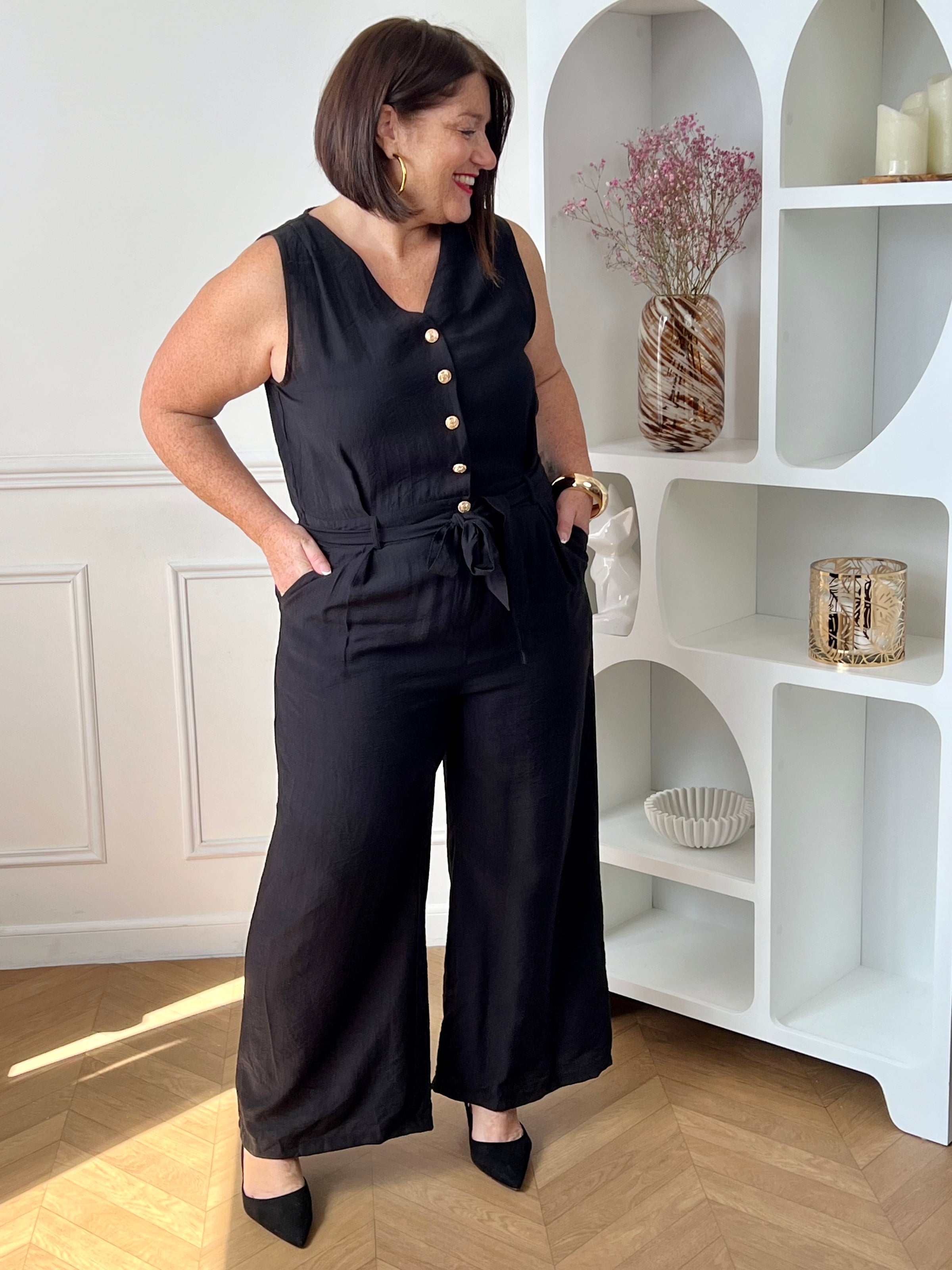 Combinaison longue femme, élégante et moderne, parfaite pour un look tendance au quotidien. Sans manches, avec un col V et des boutons dorés sur le haut, elle apporte une touche chic et raffinée. Dotée d’une ceinture amovible avec passants et d’une taille élastique au dos, elle assure un ajustement confortable. Ses deux poches latérales et sa fermeture zippée à l’avant allient praticité et style.