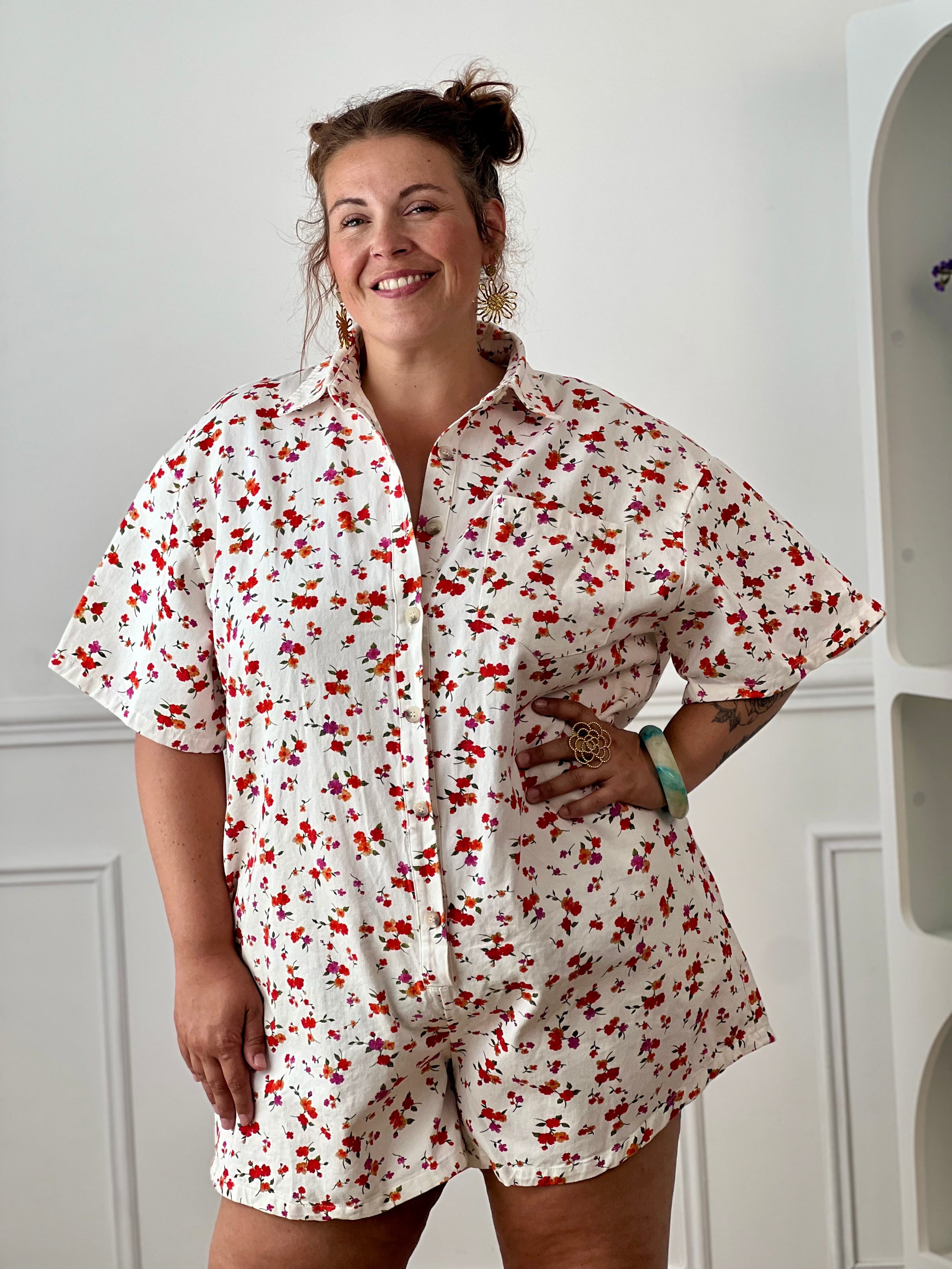 Craquez pour ce combishort grande taille au style à la fois tendance et confortable. Sa coupe ample, son col chemise et ses manches courtes en font une pièce idéale pour les journées ensoleillées. Doté d'une poche poitrine, de deux poches latérales pratiques et de boutons jusqu'à mi-longueur, il allie style et fonctionnalité. Ses motifs fleuris aux nuances d'écru, rouge, orange, vert et violet apportent une touche de fraîcheur et de féminité à vos tenues estivales.