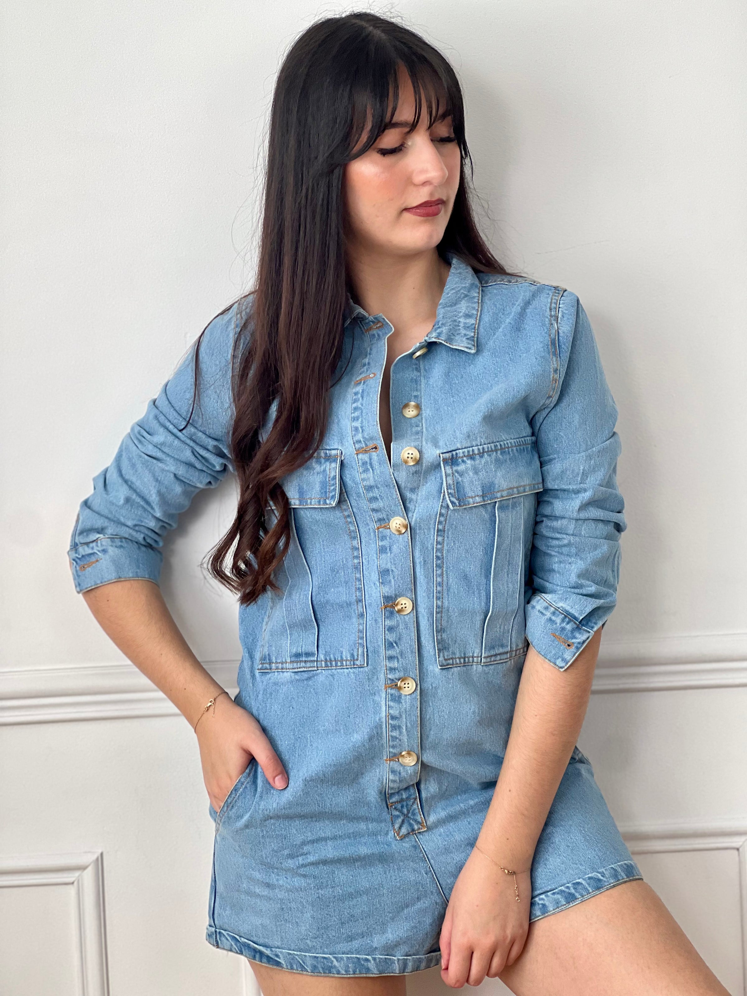 Combishort en jean bleu femme, idéal pour un look tendance et décontracté. Avec ses manches longues, son col chemise et ses boutons sur toute la longueur, il allie style et praticité. Doté de quatre poches à l’avant et de deux poches à l’arrière, il offre un côté fonctionnel au quotidien. Ses coutures camel apportent une touche contrastée et moderne. Un indispensable pour une tenue casual chic.
