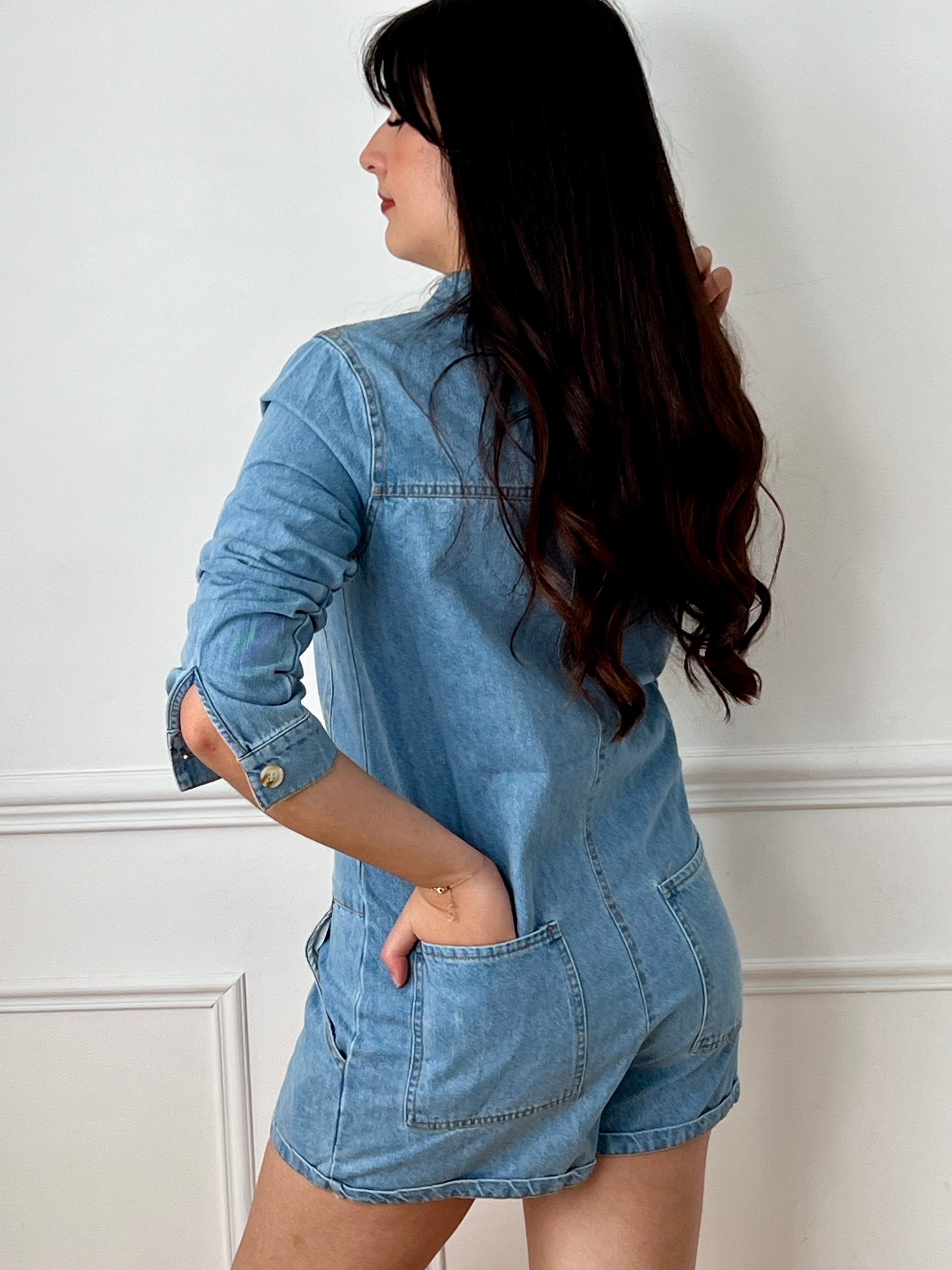 Combishort en jean bleu femme, idéal pour un look tendance et décontracté. Avec ses manches longues, son col chemise et ses boutons sur toute la longueur, il allie style et praticité. Doté de quatre poches à l’avant et de deux poches à l’arrière, il offre un côté fonctionnel au quotidien. Ses coutures camel apportent une touche contrastée et moderne. Un indispensable pour une tenue casual chic.
