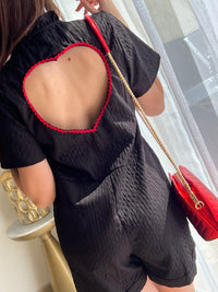 Combishort noir pour femme au design élégant et féminin, avec dos nu orné d’un cœur rouge pour une touche originale. Doté de manches courtes, d’un col montant à volants et de boutons dorés sur toute la longueur, il allie chic et modernité. Sa combinaison de couleurs noir et rouge en fait une pièce idéale pour un look sophistiqué et tendance.