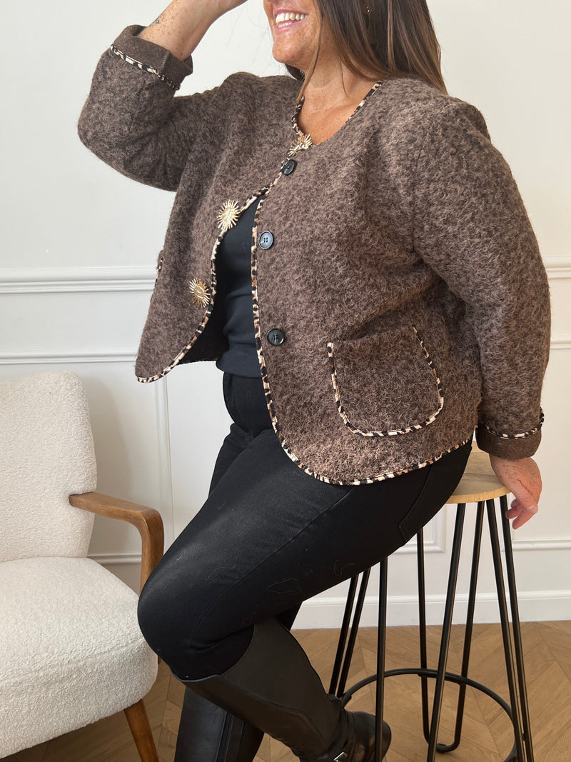 Chic et audacieuse, cette veste marron se démarque par son pourtour souligné d’une fine bande léopard, subtile touche de caractère. Pratique et élégante, elle est dotée de deux poches à l’avant et s’agrémente d’épingles amovibles dorées, offrant la possibilité de personnaliser votre look au gré de vos envies.