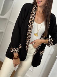 Ce blazer noir, nommé Axella, allie élégance et originalité. Ses manches longues et ses deux poches factices sur le devant offrent une silhouette structurée, tandis que le détail léopard qui court le long des poches et des revers de manches apporte une touche audacieuse et moderne.