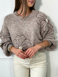 Ce pull beige foncé pour femme se distingue par ses détails délicats et élégants. Conçu avec des manches longues et un col rond classique, il offre un confort idéal tout en apportant une touche de féminité. Les fleurs brodées, ornées de petites perles, ajoutent une note subtile de raffinement, rendant ce pull unique et chic. Parfait pour les saisons fraîches, ce pull s'associe facilement avec des tenues décontractées comme habillées. La couleur beige foncé et les motifs floraux rehaussés de perles font de c