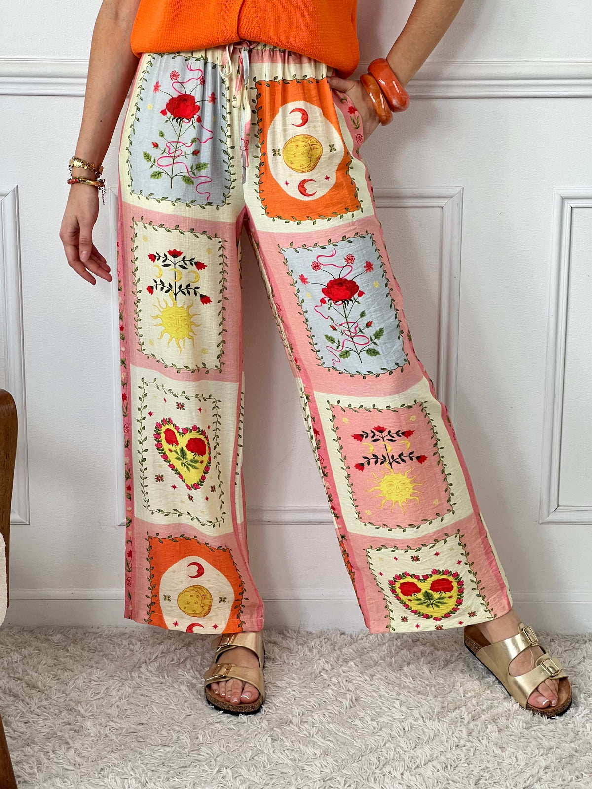 Ce pantalon Orelia coloré pour femme allie style et confort. Avec ses motifs de soleil, lune et rose et sa taille élastique avec cordon, il est à la fois léger et pratique avec ses 2 poches latérales.&nbsp;