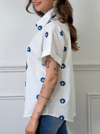 Découvrez notre chemise blanche et bleue : Jihane ! Avec ses manches courtes et sa broderie de fleurs bleues et blanches, cette chemise est à la fois élégante et décontractée. Ajoutez une touche de couleur à votre tenue tout en restant chic.