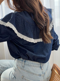 Cette chemise bleue Elyna allie élégance et confort avec son col classique et ses manches élastiques qui facilitent le mouvement. Les boutons sur toute la longueur permettent un enfilage pratique, tandis que le volant orné d'une broderie écrue apporte une touche délicate et raffinée.