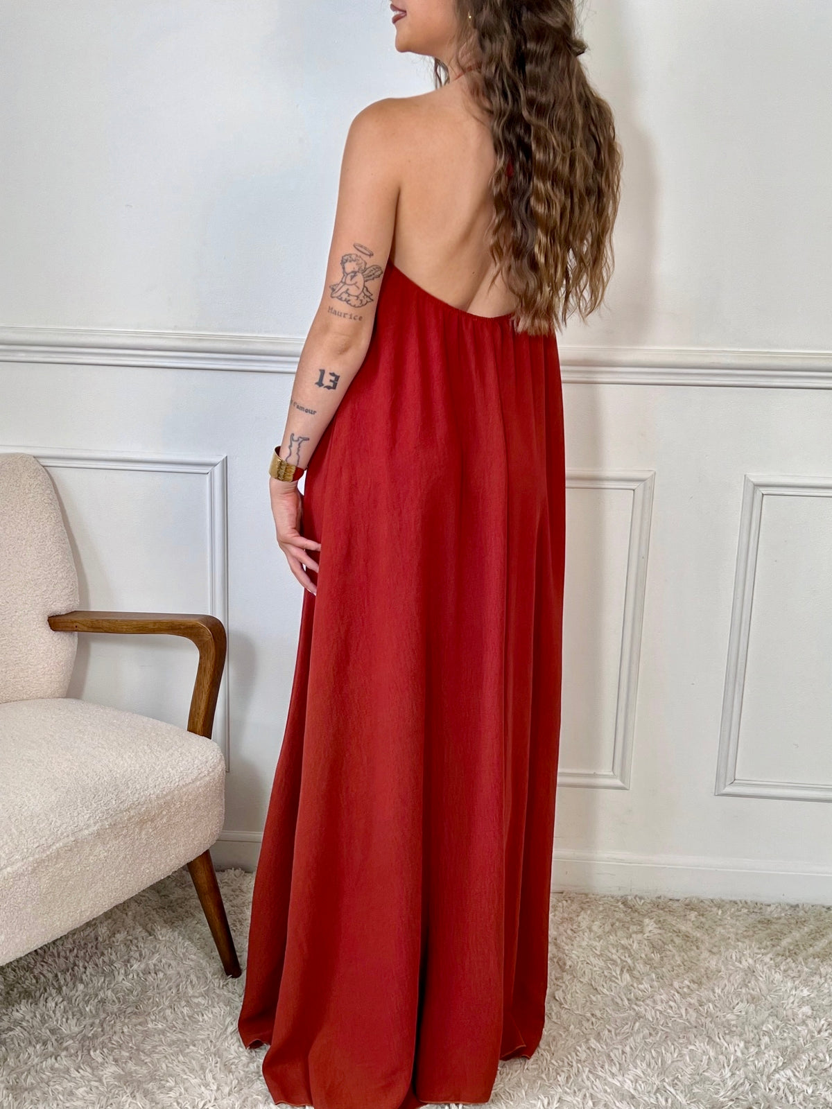Adoptez une allure audacieuse avec cette robe longue terracotta Adeje. Son col montant réglable, orné d’un détail doré, apporte une touche sophistiquée tandis que l’élastique au dos assure un confort parfait. Sans manches et à la coupe ample, elle offre une liberté de mouvement idéale pour affirmer votre style avec assurance.&nbsp;