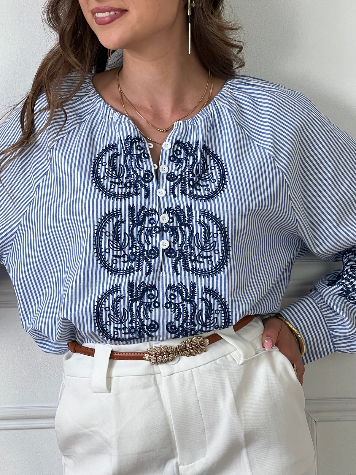 Cette blouse associe des rayures bleues et écrues élégantes à de délicats motifs floraux pour un look à la fois classique et féminin. Parfaite pour ajouter une touche de fraîcheur et de sophistication à votre tenue quotidienne.