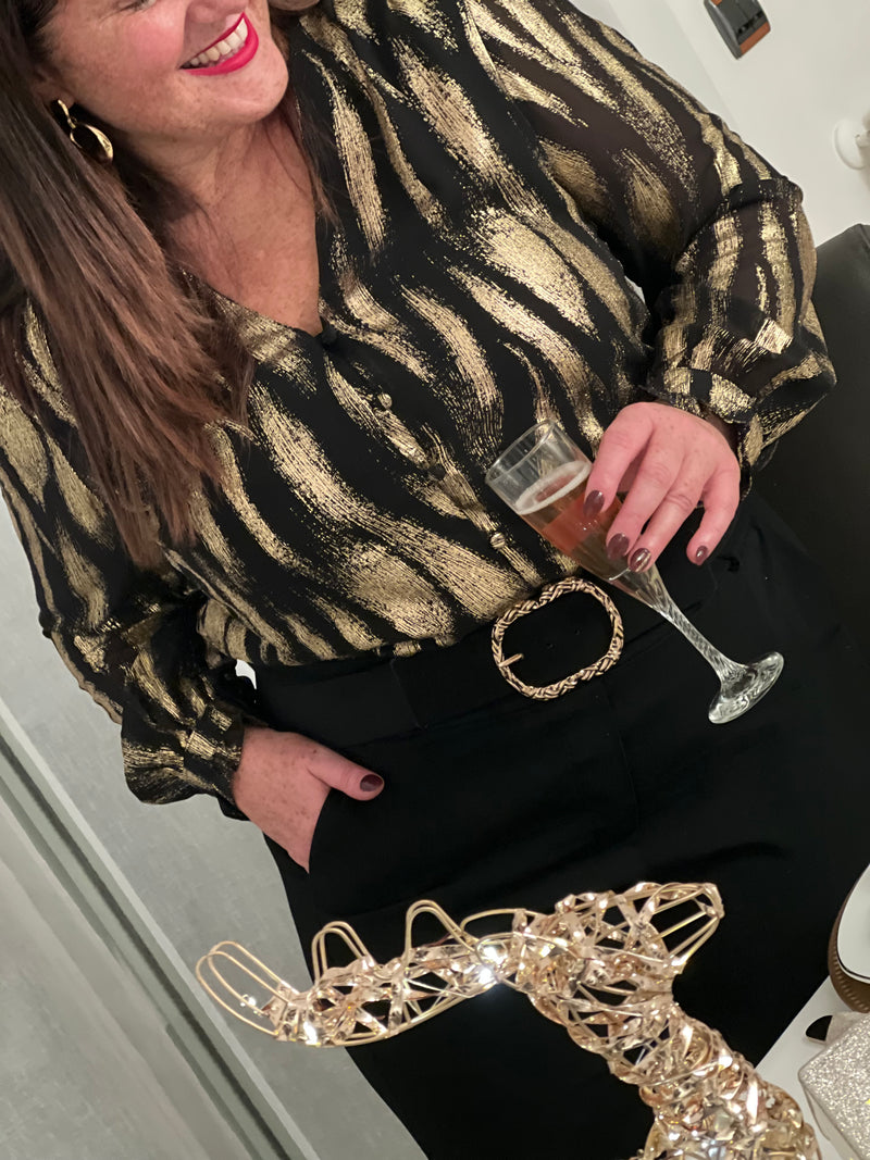 Découvrez la chemise Laina, une pièce festive qui allie élégance et confort. Avec son col V plongeant et ses manches longues ornées de volants délicats, elle crée une silhouette flatteuse et sophistiquée.