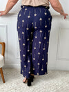 On craque pour ce pantalon bleu marine fluide et raffiné, habillé de délicats motifs palmier beige. Idéal pour un look à la fois chic et dépaysant, parfait en toute saison.