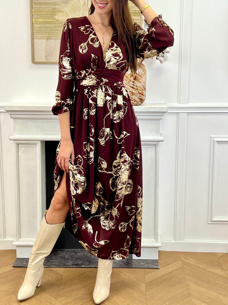 Robe longue bordeaux élégante aux détails dorés, idéale pour les occasions spéciales. Son col V et ses manches longues apportent une touche raffinée, tandis que l’élastique au dos assure un confort parfait. Entièrement doublée jusqu’à mi-longueur, elle allie style et aisance dans des nuances subtiles de bordeaux et doré.