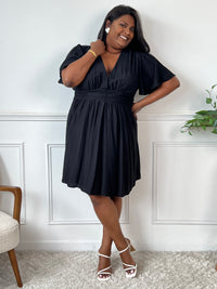 Cette robe courte noire allie confort et élégance grâce à sa taille élastique au dos qui s’adapte parfaitement à votre silhouette. Ses manches courtes et son col en V apportent une touche de fraîcheur, tandis que la doublure en bas assure un tombé fluide et agréable.