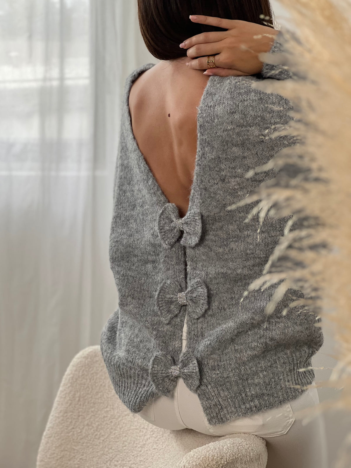 Ce pull gris à manches longues, modèle Elvie, se distingue par ses trois nœuds élégants ornés de détails en strass sur le devant. Confortable et raffiné, il apporte une touche délicate et féminine à vos tenues quotidiennes tout en restant facile à porter.
