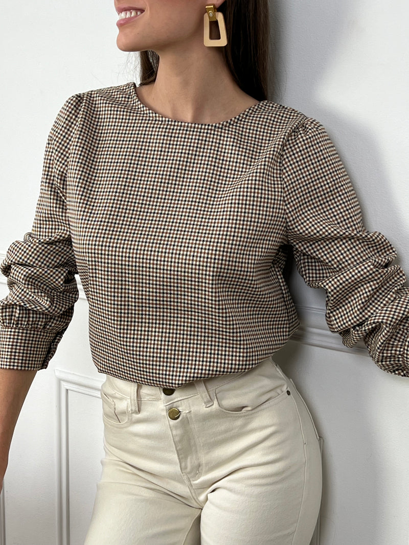 Un incontournable à ajouter à votre dressing ! Cette blouse à carreaux, avec son col V élégant et ses manches longues, offre une allure moderne et féminine. La fente subtile sur le devant, accompagnée de ses boutons raffinés au niveau du décolleté et des poignets, lui donne une touche de caractère. Idéale pour une tenue chic et décontractée, elle s'accorde aussi bien avec un jean qu'une jupe crayon