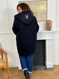Découvrez notre manteau mi-long bleu marine élégant et tendance, orné de détails léopards sur la capuche et les manches. Pratique et confortable, il dispose de deux poches à l’avant et de boutons sur toute la longueur. Avec sa capuche et son style raffiné, il allie chaleur, originalité et modernité pour un look unique en toute saison.