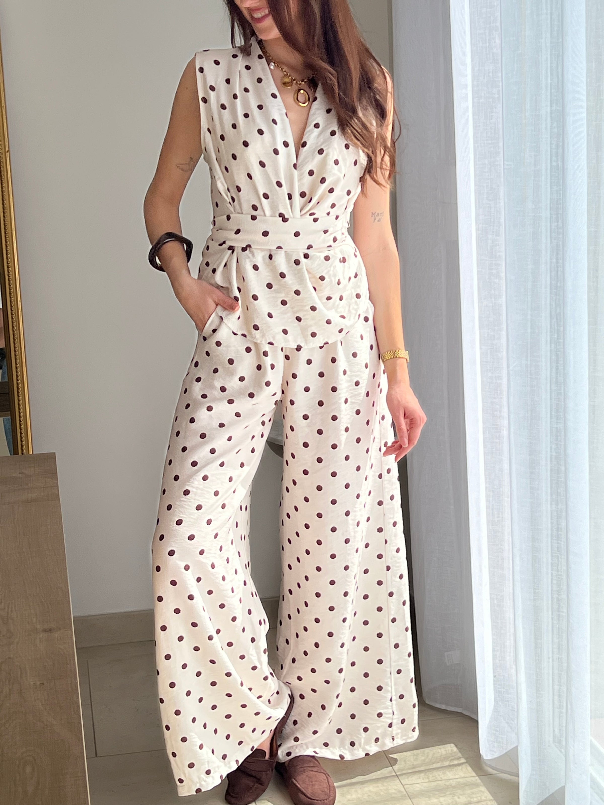 Ensemble femme élégant composé d’un top sans manches à col cache-cœur avec lien à la taille et d’un pantalon fluide assorti à pois. Sa teinte beige à pois marron apporte une touche chic et intemporelle. Fabriqué en Italie, cet ensemble est idéal pour un look raffiné au quotidien.