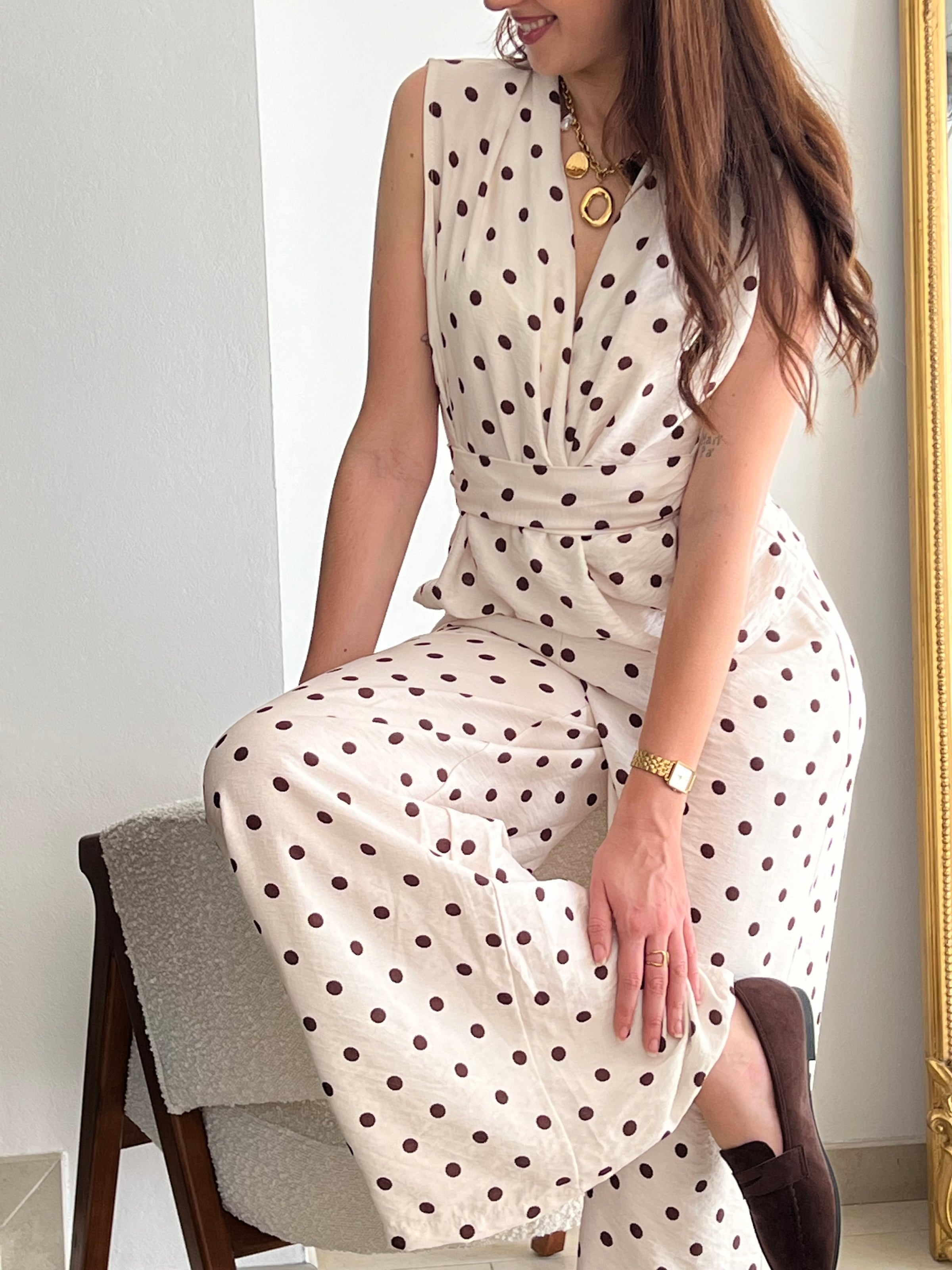 Ensemble femme élégant composé d’un top sans manches à col cache-cœur avec lien à la taille et d’un pantalon fluide assorti à pois. Sa teinte beige à pois marron apporte une touche chic et intemporelle. Fabriqué en Italie, cet ensemble est idéal pour un look raffiné au quotidien.