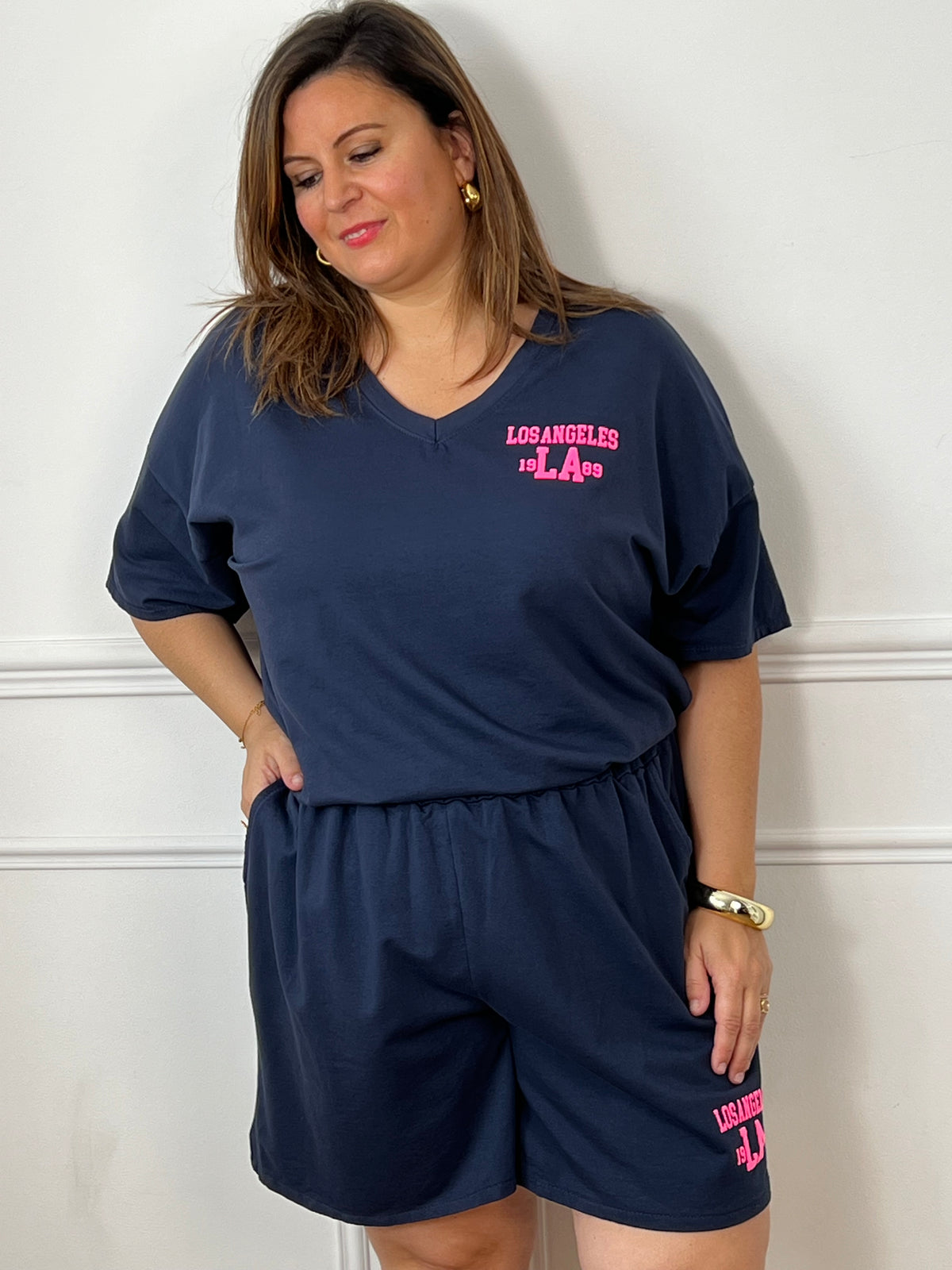 Craquez pour cet ensemble type jogging grande taille, parfait pour allier confort et style au quotidien. Composé d’un tee-shirt à manches courtes avec col V et d’un short à taille élastique doté de deux poches latérales, il offre une coupe agréable et facile à porter. Son flocage en relief rose fluo « Los Angeles » apporte une touche tendance et moderne qui contraste élégamment avec le bleu marine.&nbsp;