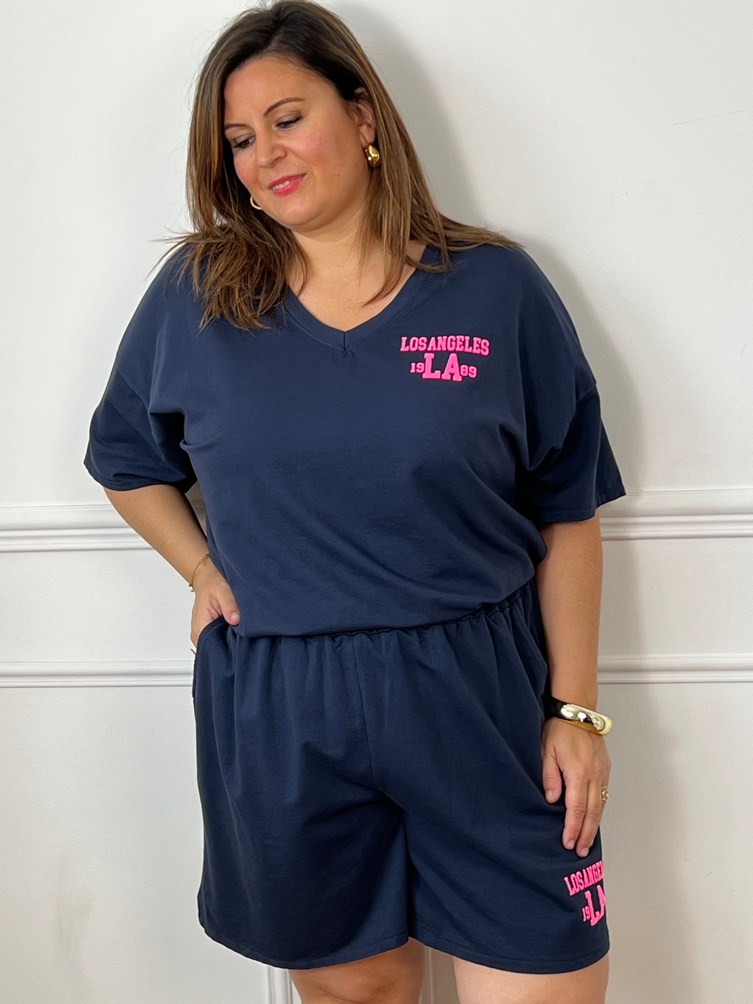 Craquez pour cet ensemble type jogging grande taille, parfait pour allier confort et style au quotidien. Composé d’un tee-shirt à manches courtes avec col V et d’un short à taille élastique doté de deux poches latérales, il offre une coupe agréable et facile à porter. Son flocage en relief rose fluo « Los Angeles » apporte une touche tendance et moderne qui contraste élégamment avec le bleu marine.&nbsp;