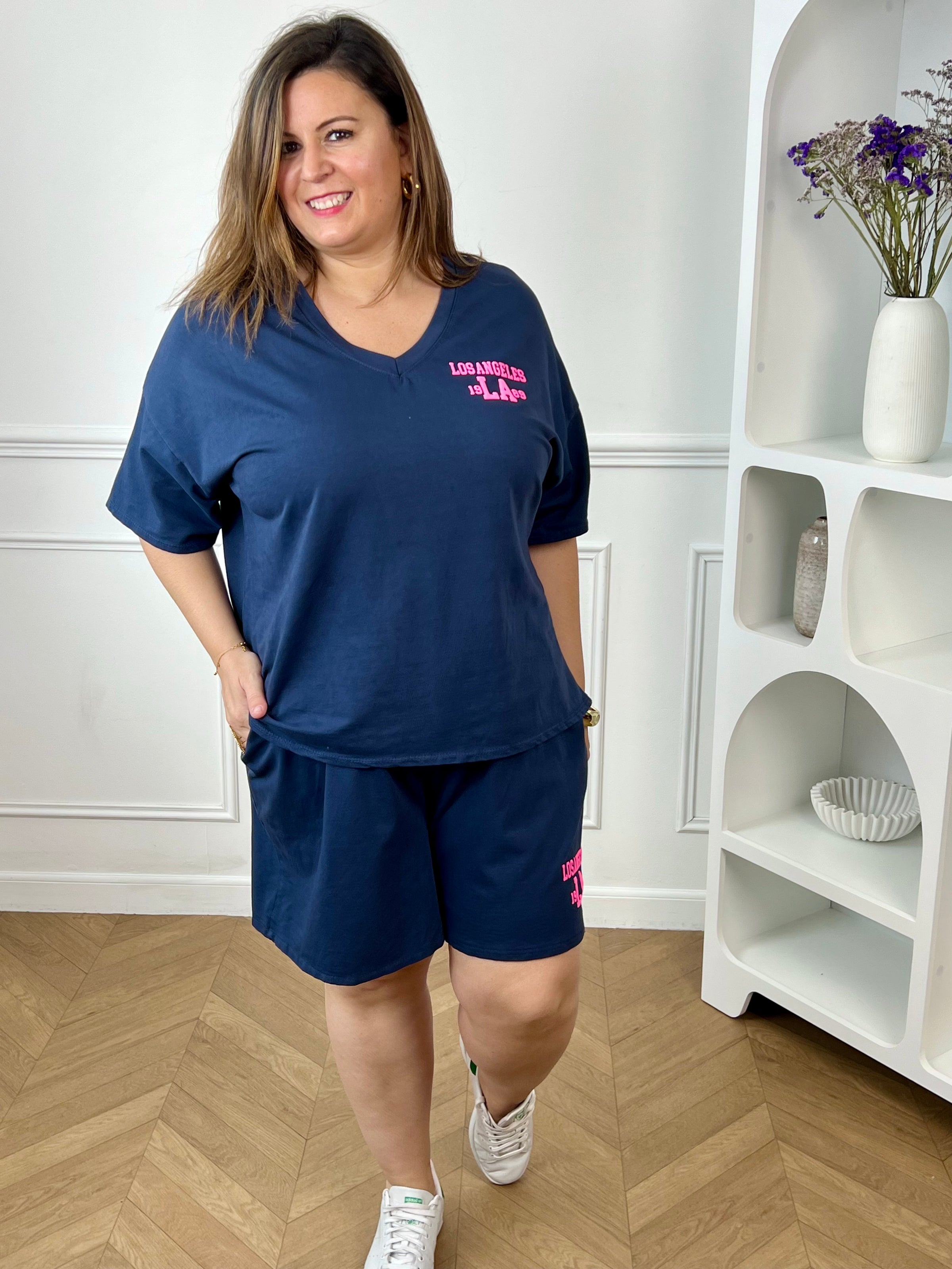 Craquez pour cet ensemble type jogging grande taille, parfait pour allier confort et style au quotidien. Composé d’un tee-shirt à manches courtes avec col V et d’un short à taille élastique doté de deux poches latérales, il offre une coupe agréable et facile à porter. Son flocage en relief rose fluo « Los Angeles » apporte une touche tendance et moderne qui contraste élégamment avec le bleu marine.&nbsp;