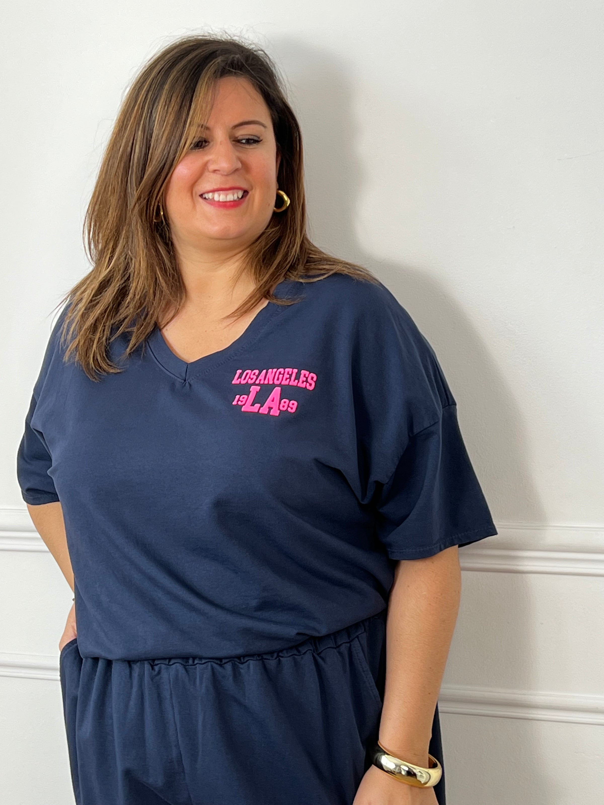 Craquez pour cet ensemble type jogging grande taille, parfait pour allier confort et style au quotidien. Composé d’un tee-shirt à manches courtes avec col V et d’un short à taille élastique doté de deux poches latérales, il offre une coupe agréable et facile à porter. Son flocage en relief rose fluo « Los Angeles » apporte une touche tendance et moderne qui contraste élégamment avec le bleu marine.&nbsp;