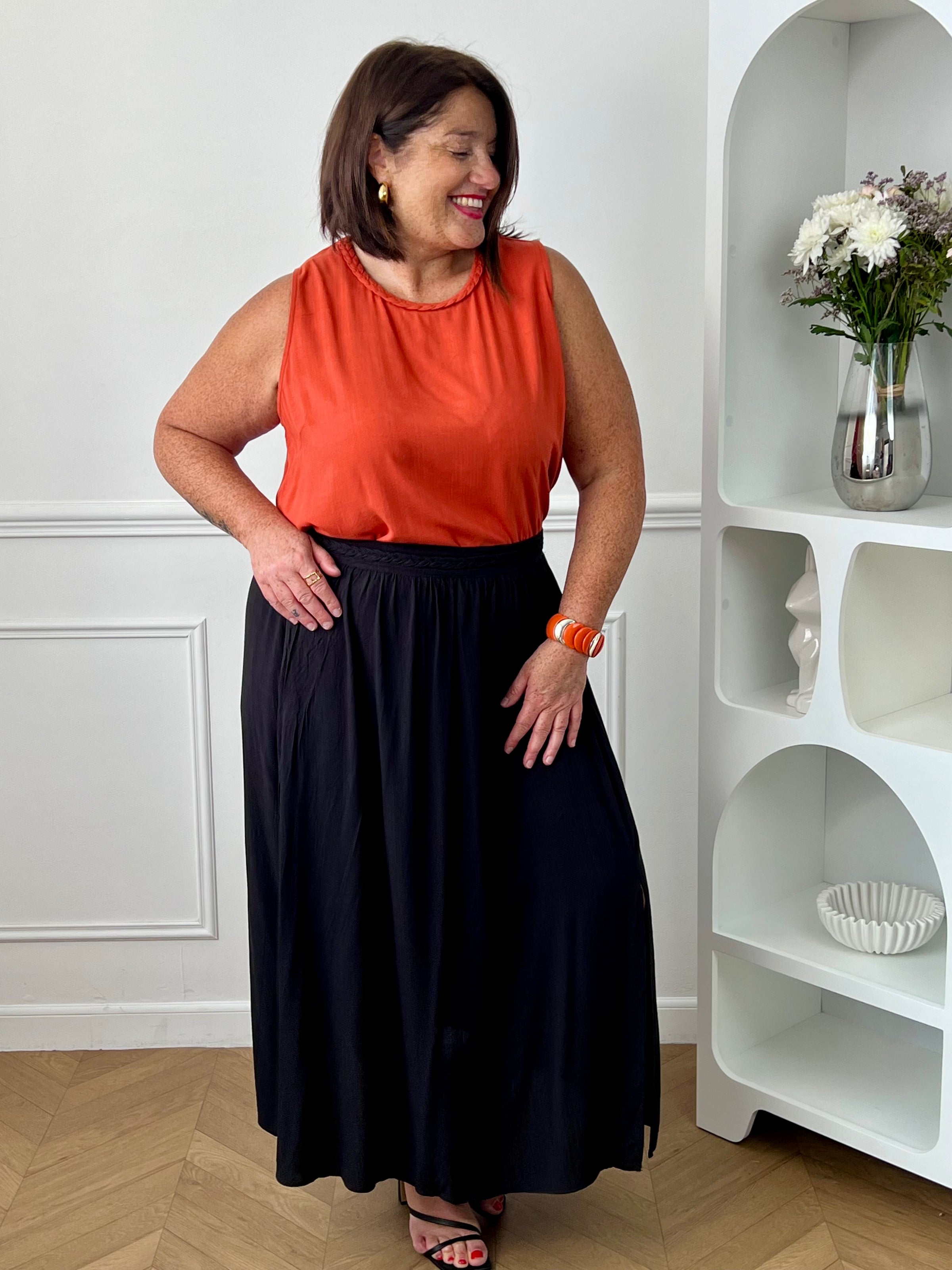 Craquez pour cet ensemble blouse et jupe noire grande taille au style élégant et raffiné. La jupe longue à coupe fluide se distingue par sa fente sur le côté, sa tresse à la taille et son élastique au dos pour un confort optimal. La blouse sans manches, dotée d’un col rond avec détail tressé et d’une ouverture au dos avec bouton, apporte une touche féminine et sophistiquée.