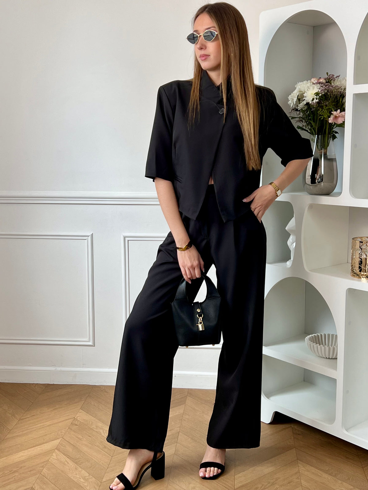 Ensemble veste et pantalon femme noir, élégant et moderne, parfait pour un look chic au quotidien. La veste courte à manches courtes se distingue par son col montant, ses poches factices à l’avant et son bouton au niveau du col pour une touche sophistiquée. Le pantalon à coupe droite, avec fermeture zippée et bouton, passants pour ceinture, poches latérales et taille élastique au dos, offre confort et élégance.