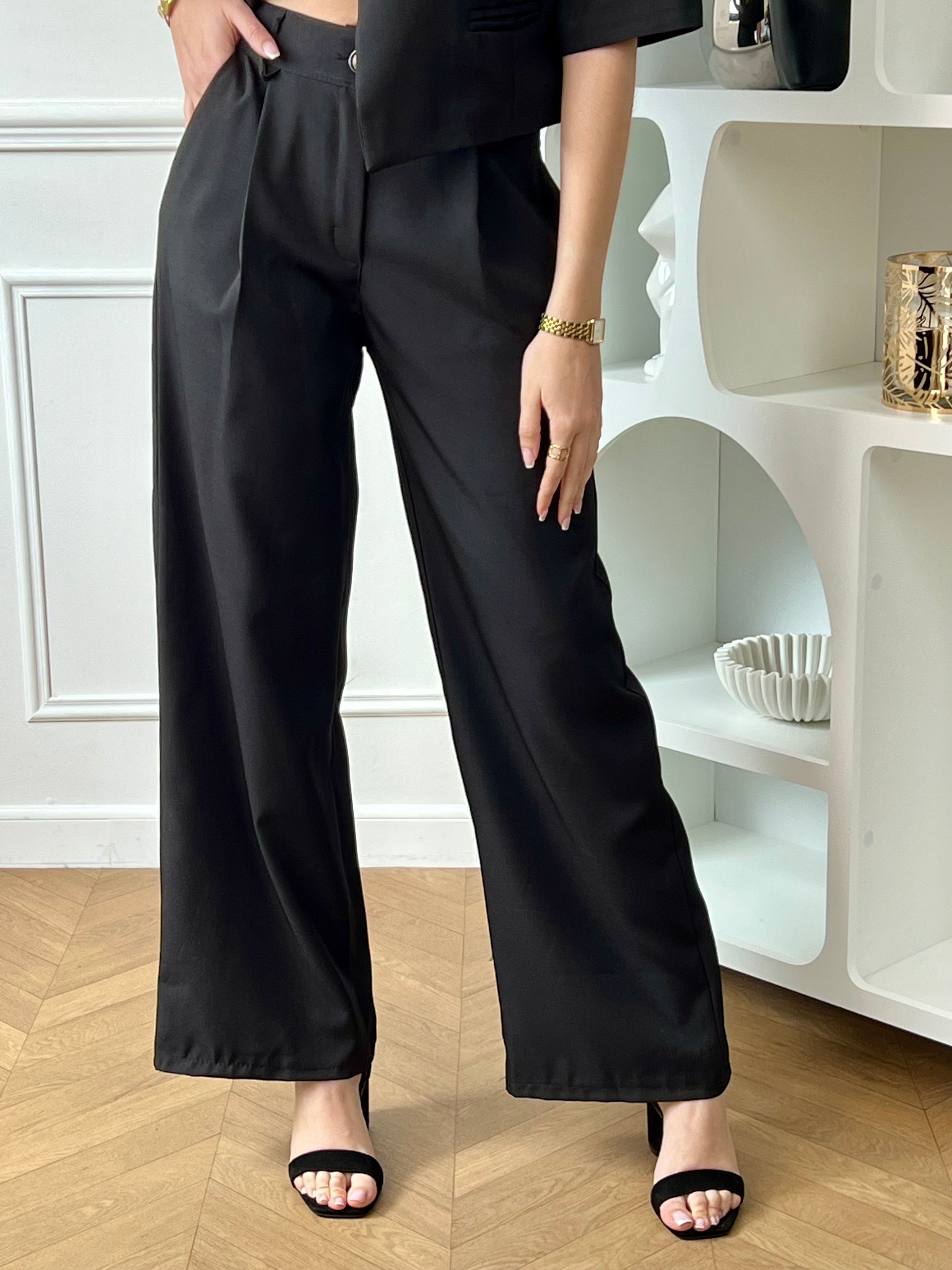 Ensemble veste et pantalon femme noir, élégant et moderne, parfait pour un look chic au quotidien. La veste courte à manches courtes se distingue par son col montant, ses poches factices à l’avant et son bouton au niveau du col pour une touche sophistiquée. Le pantalon à coupe droite, avec fermeture zippée et bouton, passants pour ceinture, poches latérales et taille élastique au dos, offre confort et élégance.