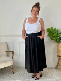 La jupe noire plissée de grande taille incarne une élégance intemporelle. Avec sa coupe longue, elle offre une silhouette flatteuse et tendance. Cette pièce allie style et confort, créant une tenue sophistiquée et moderne pour les femmes de grande taille.