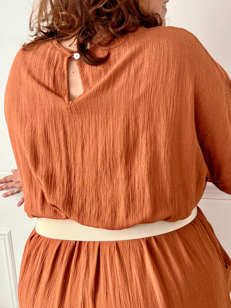 La combinaison Savanah terracotta grande taille allie confort et élégance avec son col cache-cœur, ses manches courtes et son élastique à la taille. Pratique avec ses poches latérales et son ouverture dos à bouton, elle vous met en valeur avec douceur.