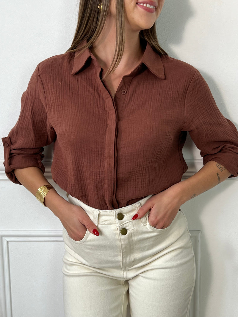 Cette chemise marron, avec ses manches longues et son col classique, est un indispensable du dressing ! Dotée de boutons tout le long et aux poignets, elle se démarque par sa coupe fluide et ses manches retroussables pour un style modulable selon l’occasion. Parfaite pour un look casual chic ou une allure plus habillée, elle s'associe aisément à un jean, un pantalon tailleur, ou même une jupe pour un look élégant et décontracté.