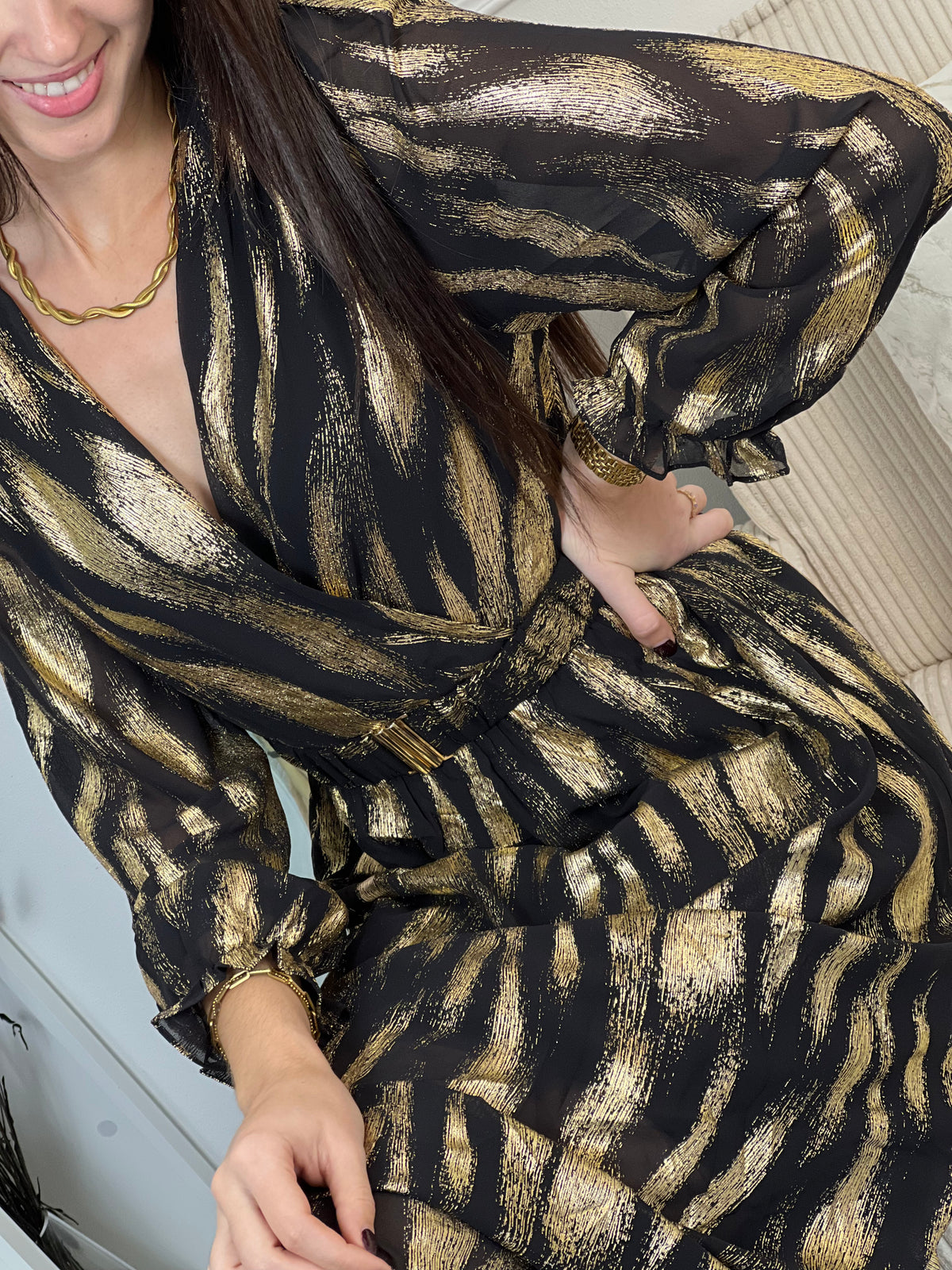 Robe festive Laina, l'allure sophistiquée pour vos soirées. Cette création élégante allie le noir profond et les touches dorées pour une présence rayonnante. Le col cache-cœur flatteuse épouse votre silhouette tandis que la taille élastique offre un confort optimal.