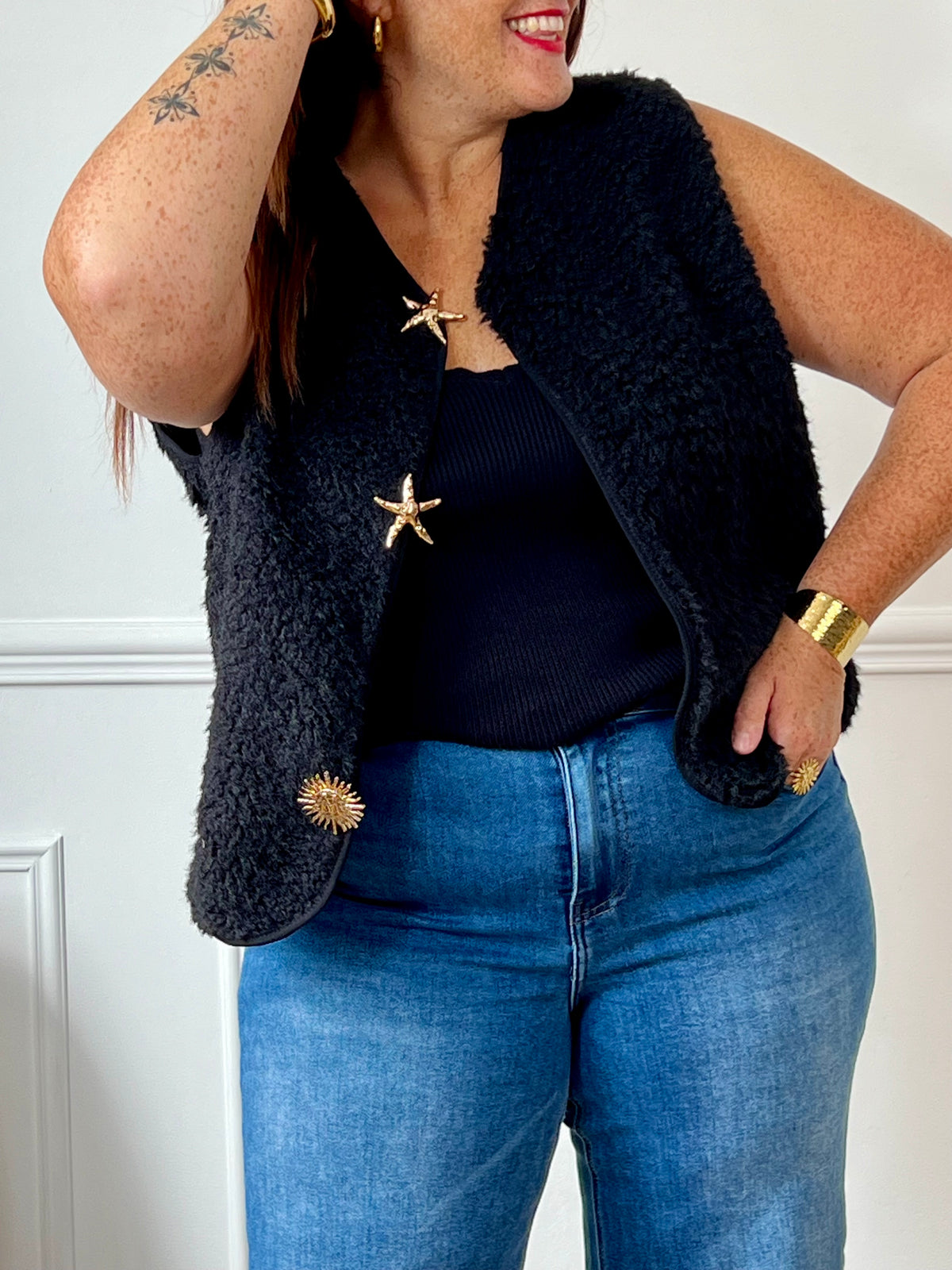 La veste moumoute sans manches Eda allie douceur et style. Conçue pour offrir un confort optimal, elle présente un col en V élégant et des broches dorées délicates sur le devant, qui ajoutent une touche sophistiquée.