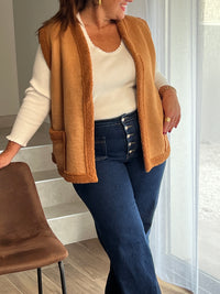 Adoptez un look tendance avec la veste sans manches Curve : Talya en imitation daim camel. Avec ses 2 poches à l'avant, elle allie style et praticité. Son effet moumoute apporte une touche de douceur et de chaleur pour les journées fraîches. Soyez élégante et confortable en toutes occasions !