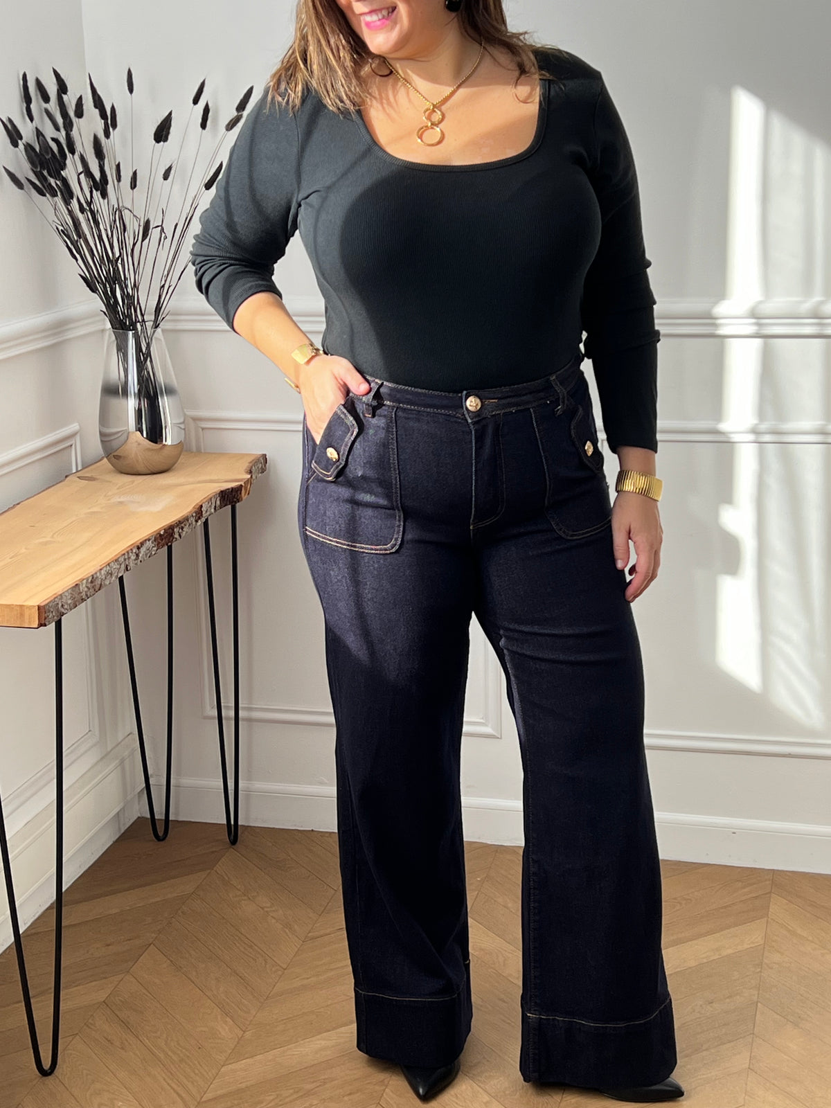 Jean bleu foncé intemporel au style affirmé. Coupe large et confortable avec jambes évasées pour une silhouette moderne. Doté de 4 poches pratiques et de détails dorés aux poches qui ajoutent une touche d'élégance.