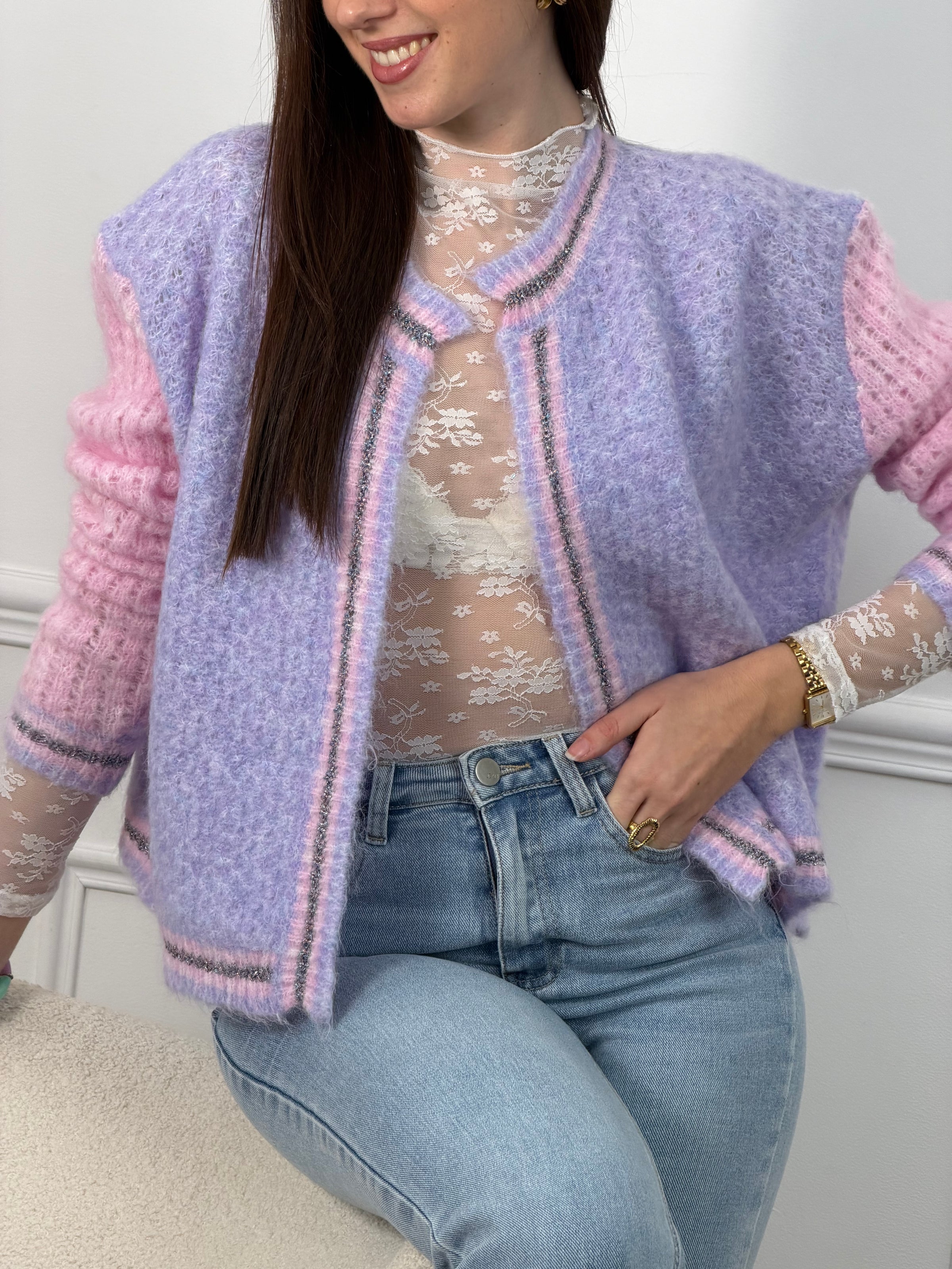 Découvrez le Gilet Nadège, une pièce incontournable alliant style et confort. Ce gilet en laine violet arbore des manches longues roses qui créent un contraste harmonieux et moderne. Son col rond épuré se complète par des bords délicatement ornés de fils colorés brillants, apportant une touche d'éclat à votre silhouette.&nbsp;