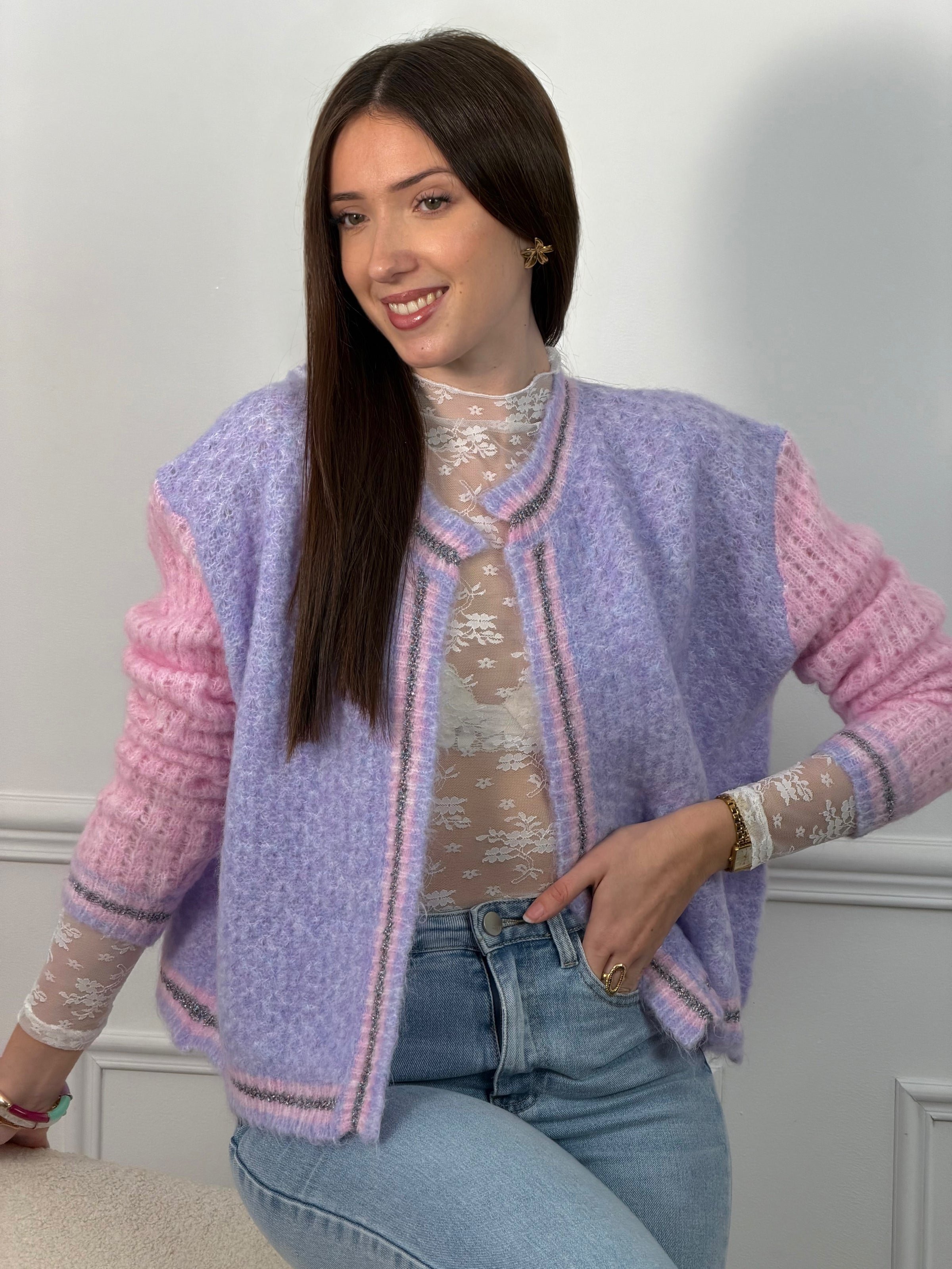 Découvrez le Gilet Nadège, une pièce incontournable alliant style et confort. Ce gilet en laine violet arbore des manches longues roses qui créent un contraste harmonieux et moderne. Son col rond épuré se complète par des bords délicatement ornés de fils colorés brillants, apportant une touche d'éclat à votre silhouette.&nbsp;