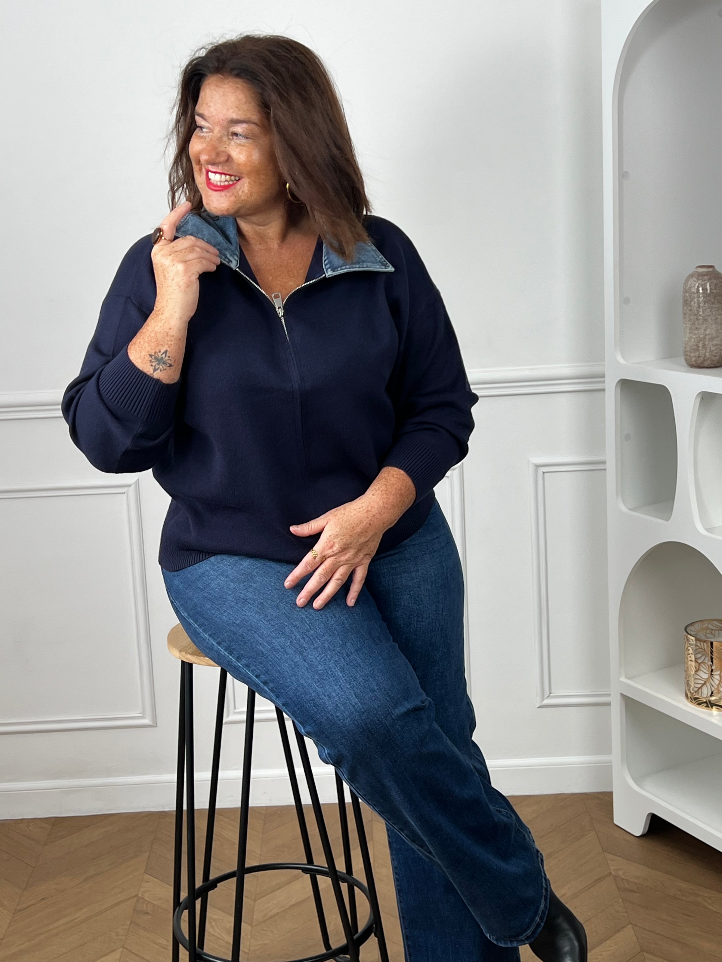 Pull marine col denim grande taille – modèle curve assise sur tabouret look décontracté et souriant – Loïcia