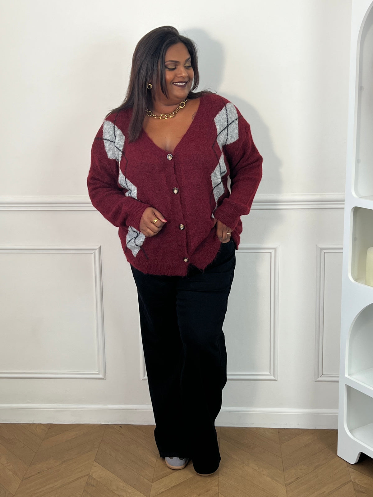 Gilet bordeaux à losanges gris porté boutonné de face avec un pantalon large noir – Isadora | Loïcia