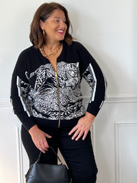 Gilet noir Elvira grande taille porté de face, avec motif léopard blanc, fermeture zippée dorée et bandes blanches sur les manches.